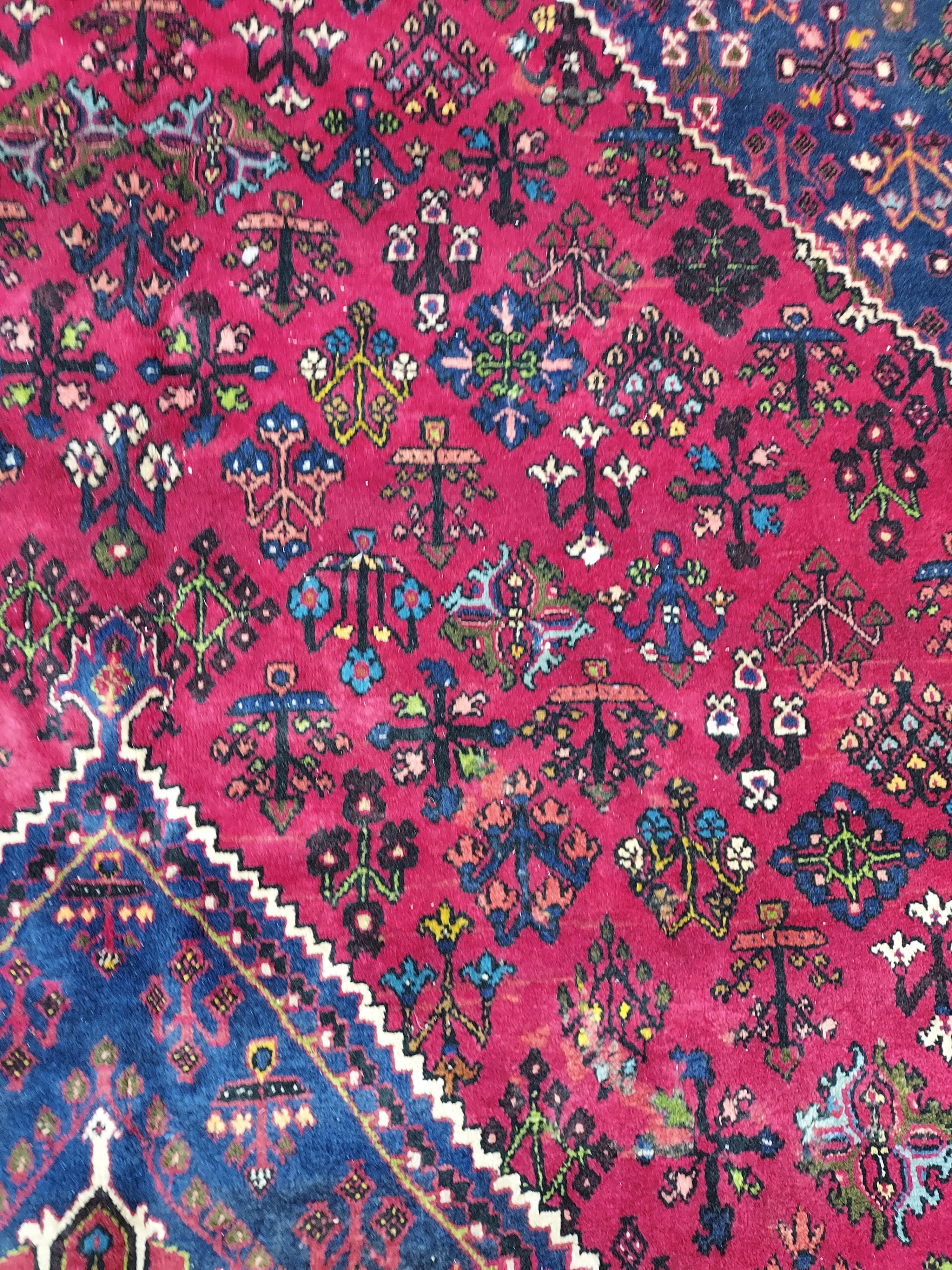 Close-up of a colorful patterned rug with intricate designs on a pink and blue background.